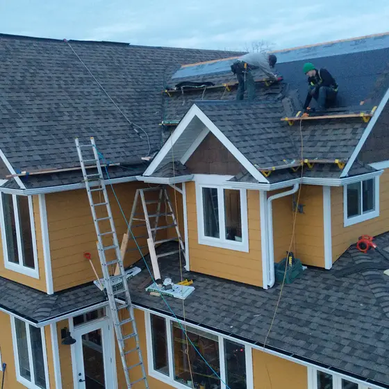 Crew installing architectural shingles on a large two-storey home
