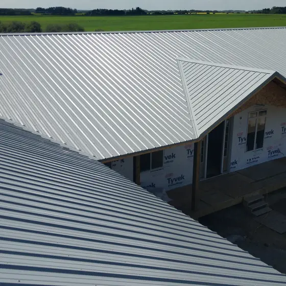 New metal roof over a wrap-around porch, farmhouse under construction