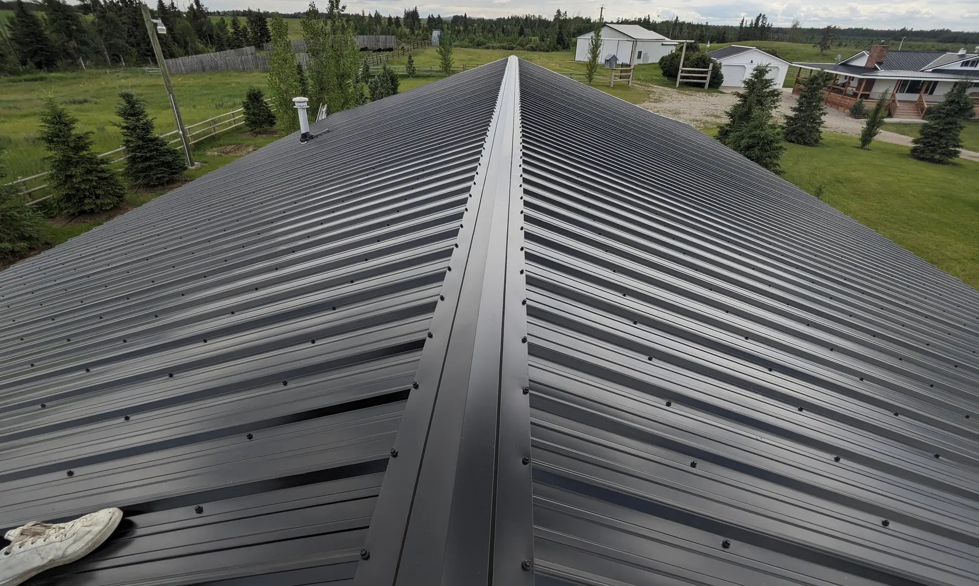 Black standing-seam metal roof ridge on an acreage home near Red Deer